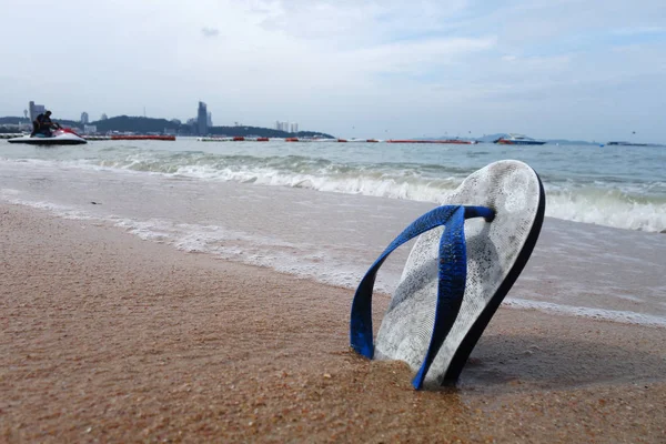 Zapatillas de playa en una playa de arena — Foto de Stock