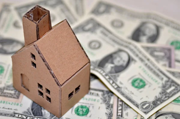 Miniature paper made house stand on  money