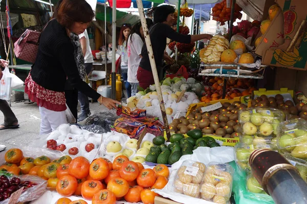 Straßenhändler verkauft Früchte auf nassem Markt in Macau. — Stockfoto