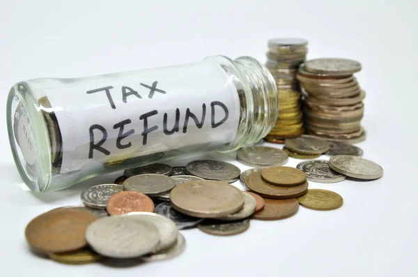 Tax refund lable in a glass jar with coins spilling out — Stock Photo, Image