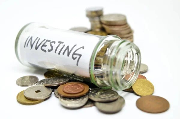 Investment lable in a glass jar with coins spilling out — Stock Photo, Image