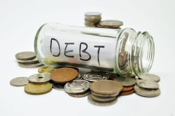 Debt lable in a glass jar with coins spilling out — Stock Photo, Image