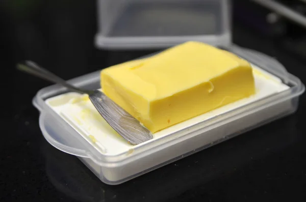 Kostka másla na černý stůl — Stock fotografie