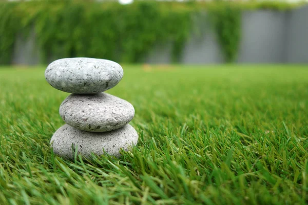 Pebbles stacked up on grass — Stock Photo, Image