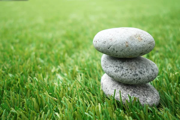 Pebbles stacked up on grass — Stock Photo, Image
