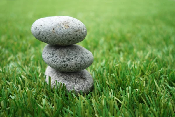 Pebbles stacked up on grass — Stock Photo, Image