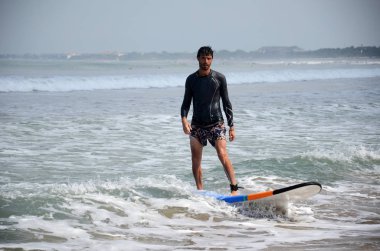 Young surfer ride on surfboard with fun on sea waves at Kuta , B