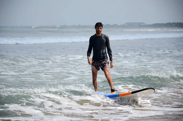 Jovem surfista passeio na prancha de surf com diversão nas ondas do mar em Kuta, B — Fotografia de Stock