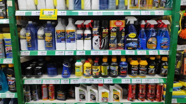 Различные автомобильные масла и моющее средство в бутылках на полках в супермаркете — стоковое фото
