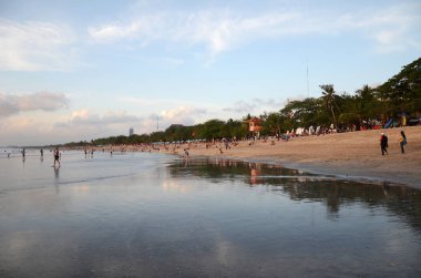 İnsanlar Kuta, Bali sahilinde dramatik günbatımının tadını çıkarıyorlar.