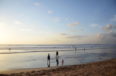 İnsanlar Kuta, Bali sahilinde dramatik günbatımının tadını çıkarıyorlar.