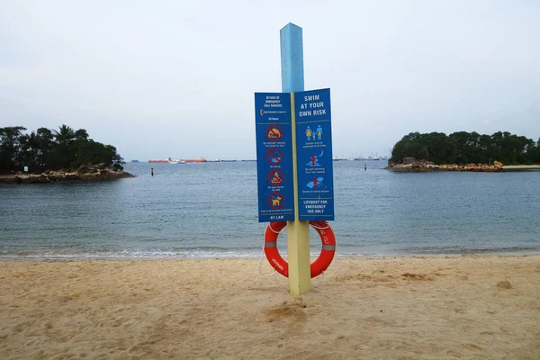 На большом деревянном щите на пляже написано: плавайте на свой страх и риск — стоковое фото