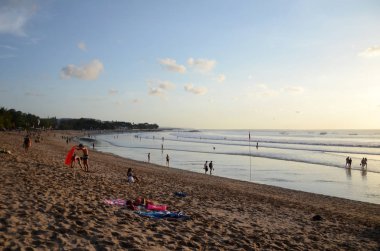 İnsanlar Kuta, Bali sahilinde dramatik günbatımının tadını çıkarıyorlar.