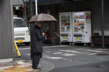 Şemsiyeli iş adamı yağmurlu bir günde karşıdan karşıya geçmek için bekliyor.