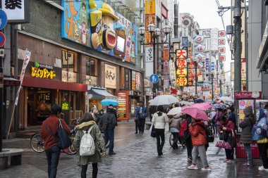 İnsanlar yağmurlu bir günde Osaka 'daki Dotonbori caddesini ziyaret ediyorlar.