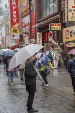 İnsanlar yağmurlu bir günde Osaka 'daki Dotonbori caddesini ziyaret ediyorlar.