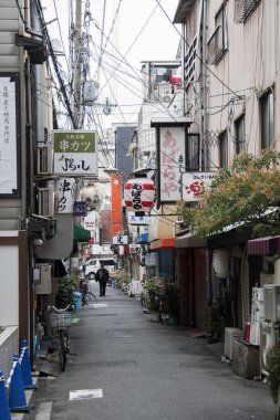 İnsanlar sabah Namba bölgesinde sessiz caddelerde yürüyorlar.