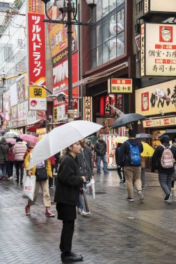 İnsanlar yağmurlu bir günde Osaka 'daki Dotonbori caddesini ziyaret ediyorlar.