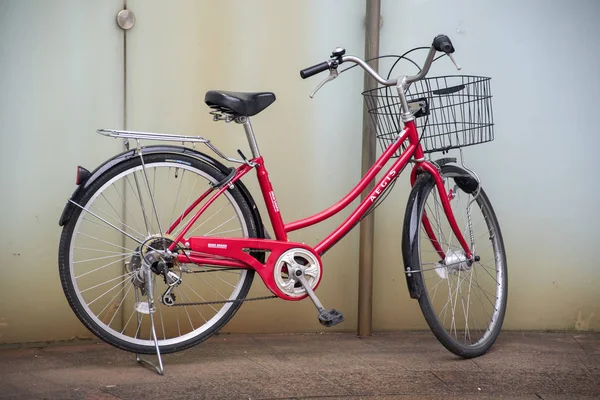 Czerwony rower jest zaparkowany przy ścianie w Osace, Japonia — Zdjęcie stockowe