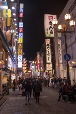 Gece vakti Dotonburi caddesinde yürüyor.