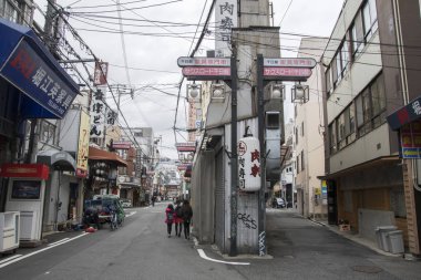 İnsanlar sabah Namba bölgesinde sessiz caddelerde yürüyorlar.