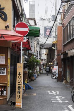İnsanlar sabah Namba bölgesinde sessiz caddelerde yürüyorlar.