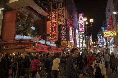 Gece vakti Dotonburi caddesinde yürüyor.