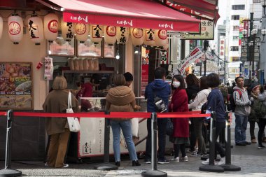 Müşteriler Takoyaki ahtapotlarının önünde kuyruğa giriyor.