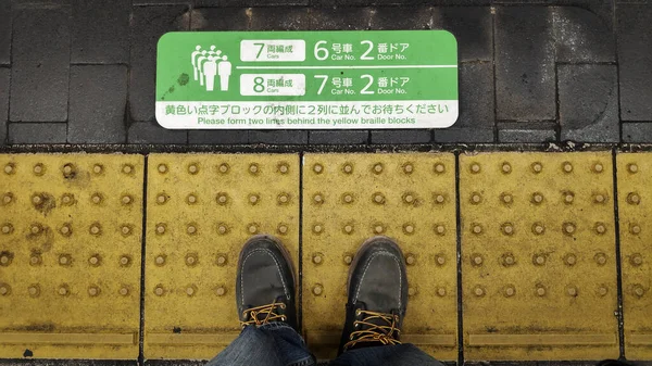 Füße stehen auf der gelben Linie neben dem Bahngleis in Kyoto — Stockfoto