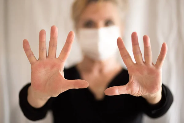 Senior woman wearing mask, shows clean hands and show stop hands gesture for stop corona virus outbreak. Coronavirus and epidemic virus symptoms.