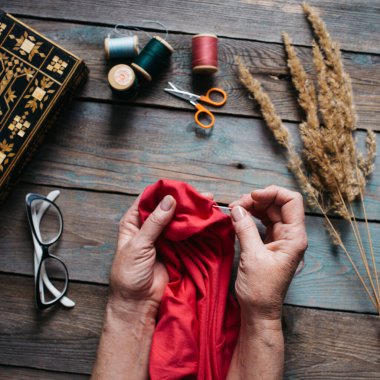 Ahşap masa üzerinde farklı aksesuarları olan kadın eli dikiş düğmesi