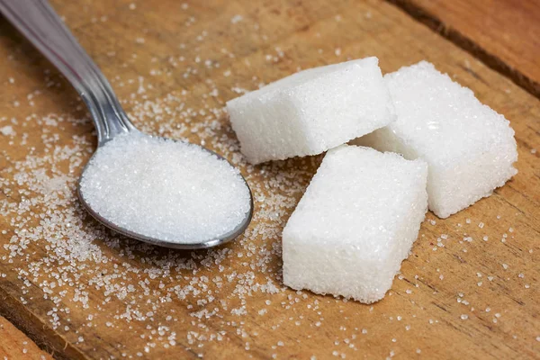 Zuckerwürfel im Löffel auf Holz Hintergrund — Stockfoto