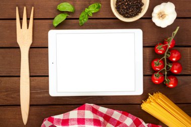 Beyaz tablet, ahşap zemin üzerinde fotokopi alanı ile İtalyan makarnası pişirmek için malzemeler, üst görünüm