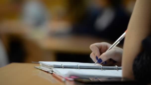 Studenten aan de Universiteit (school) in de klas. Notitieblokken, pennen, handen, close-up — Stockvideo