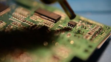 Laboratuvarda lehimleyerek akıllı telefonun ana kartını tamir eden teknisyen elinin yakın çekimi. bilgisayar donanımı, cep telefonu, elektronik, onarım, güncelleme ve teknoloji kavramı.