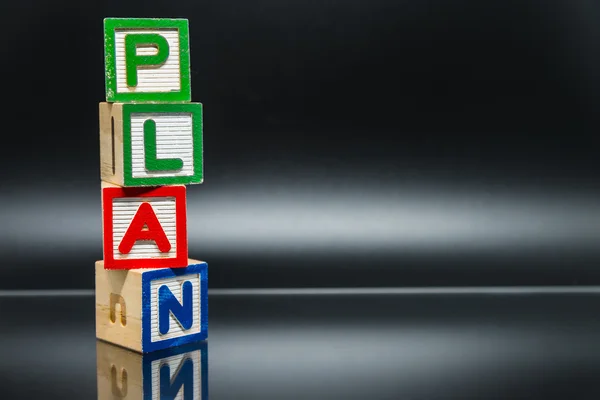 PLAN word wooden block arrange in vertical style on black background and selective focus — Stock Photo, Image