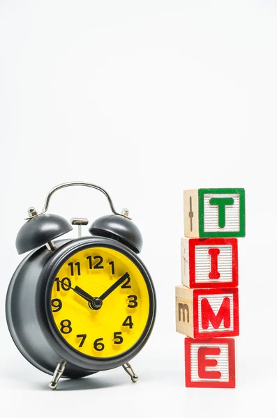 TIME palavra bloco de madeira organizar em estilo vertical com relógio de alarme retro preto no fundo branco e foco seletivo — Fotografia de Stock