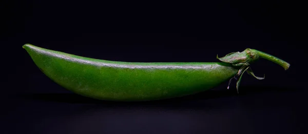 Closeup Ervilha verde fresca isolada sobre fundo preto com foco seletivo e sob exposição — Fotografia de Stock