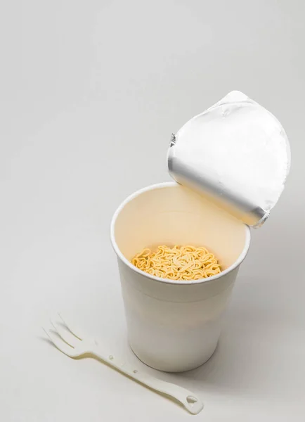 Nouilles instantanées isolées dans une tasse en papier avec fourchette en plastique sur fond blanc avec chemin de coupe — Photo