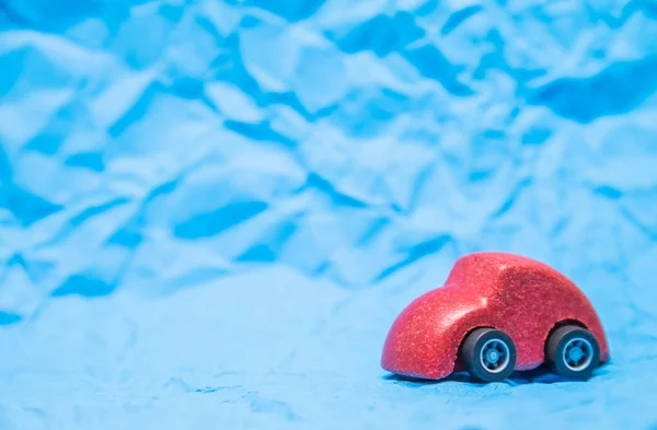Isolado brinquedo de carro de madeira vermelho no fundo de papel amassado azul — Fotografia de Stock