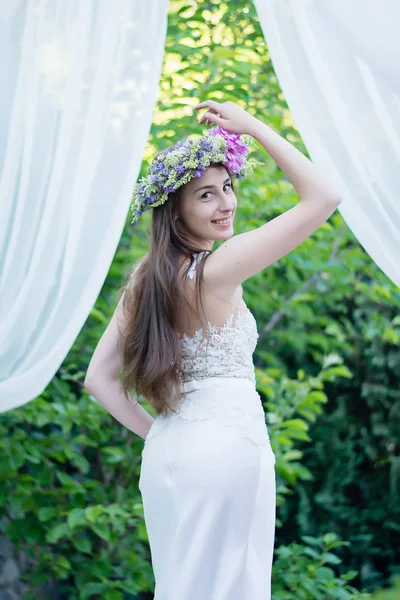 Happy bride with flowers and in a wreath outdoors