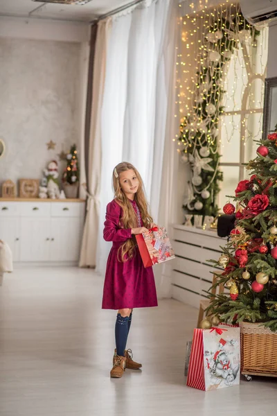 Beautiful girl gives presents. Christmas holidays at the Christmas tree