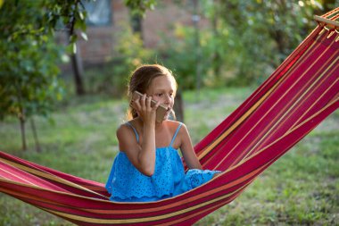 Hamakta dinlenen genç bir kadın. Genç bir kadın parkta kitap okuyor.