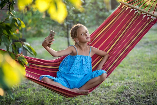 Hamakta dinlenen genç bir kadın. Genç bir kadın parkta kitap okuyor.