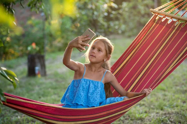 Hamakta dinlenen genç bir kadın. Genç bir kadın parkta kitap okuyor.