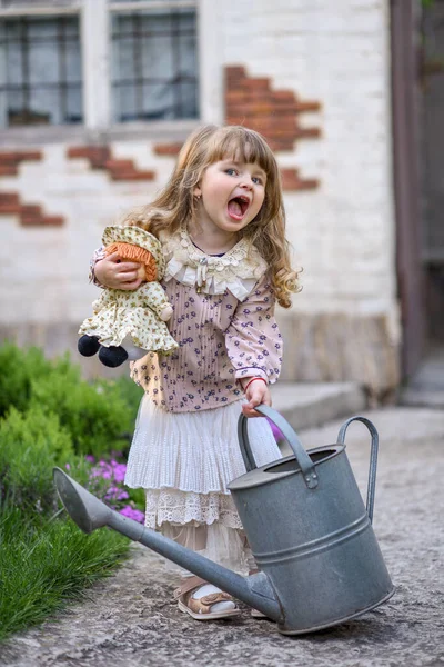 Kleines Mädchen Mit Gießkanne Und Puppe Garten — Stockfoto