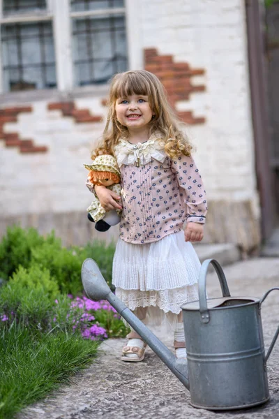 Kleines Mädchen Mit Gießkanne Und Puppe Garten — Stockfoto