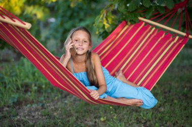 Hamakta dinlenen genç bir kadın. Parkta kitap okuyan genç bir kadın. Kız telefonda selfie çekiyor ve hamakta dinleniyor..