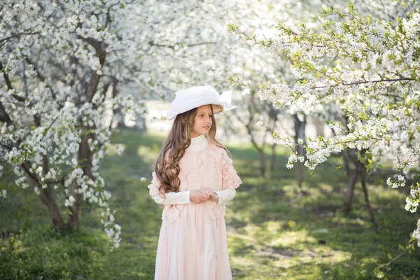 在春天的花园里 小女孩穿着粉红色的衣服 头戴一顶复古的帽子 — 图库照片