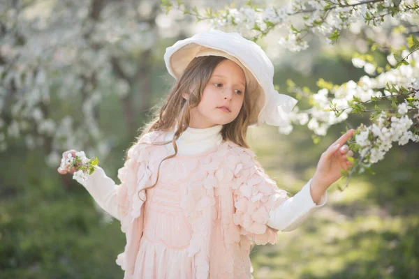 春の庭でピンクのドレスとレトロな帽子をかぶった女の子 — ストック写真